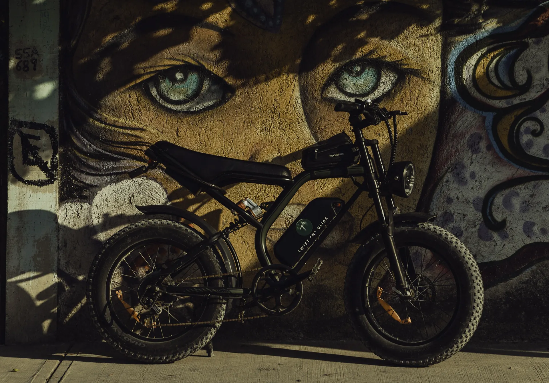 Chopper e-bike parked beside a mural in Tulum